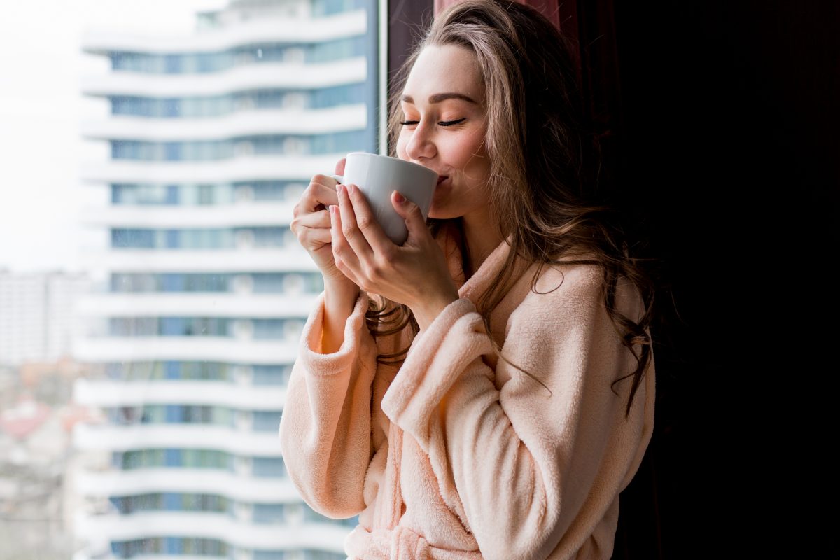 fresh young woman pink tender bathrobe drink tea looking out window